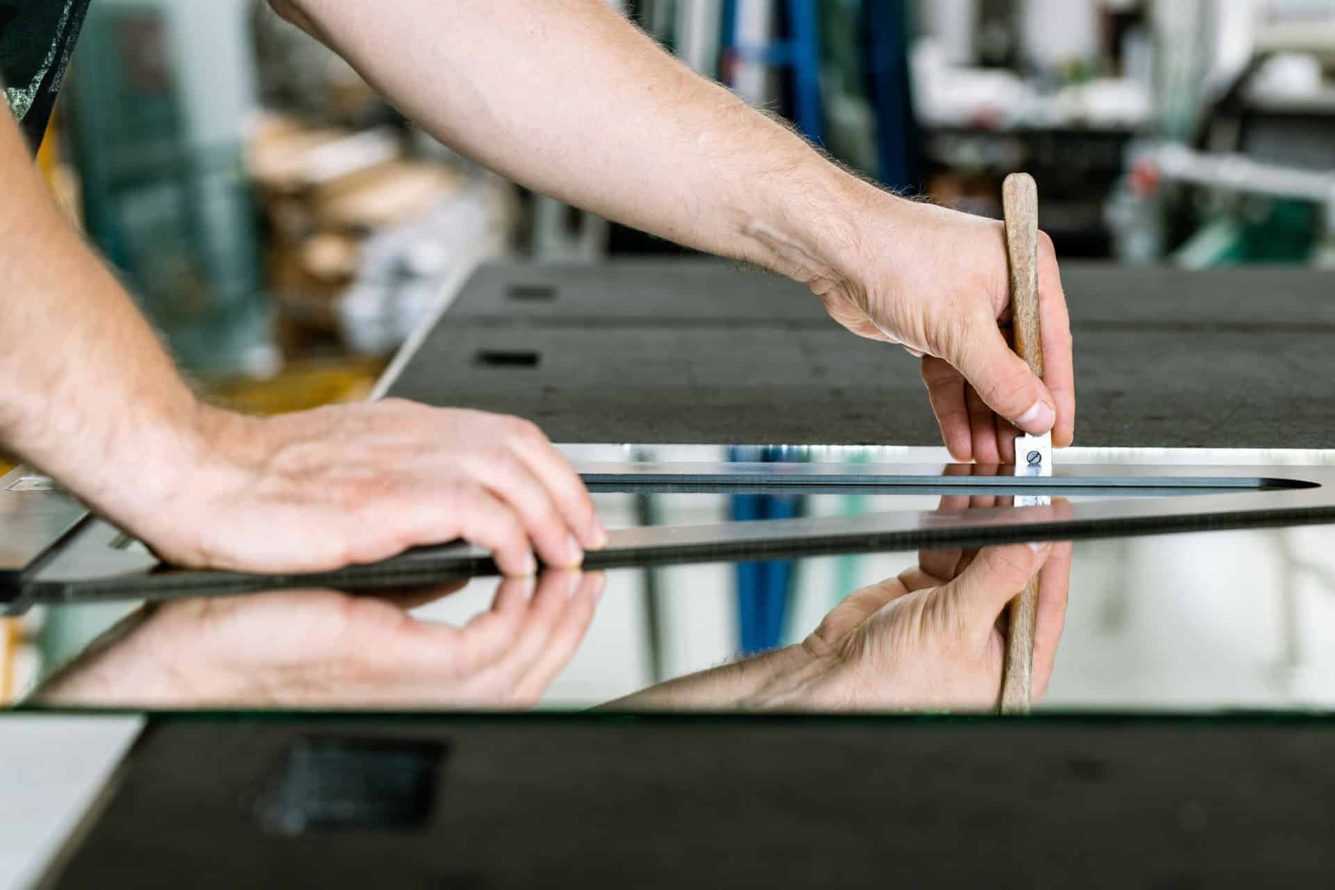 Artisan vitrier fribourgeois qui découpe un verre