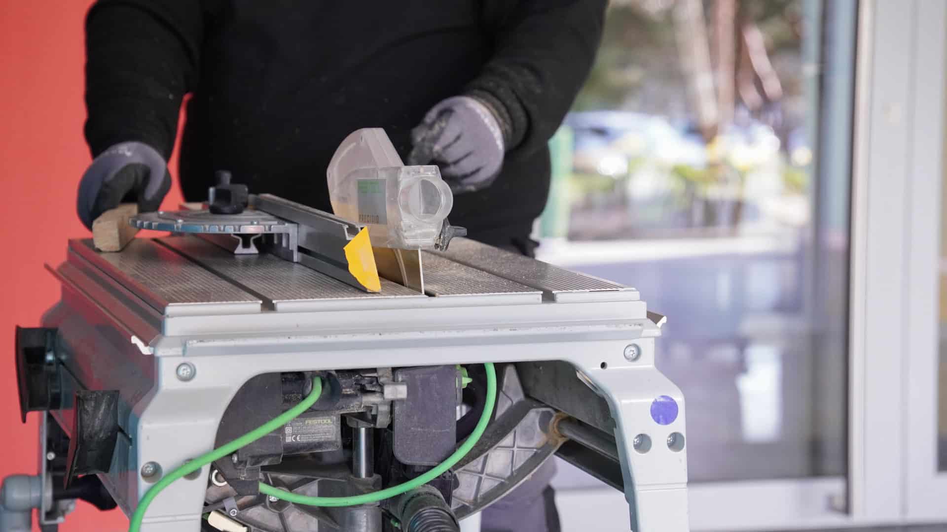 Vitrier découpant du bois sur une scie de table Festool