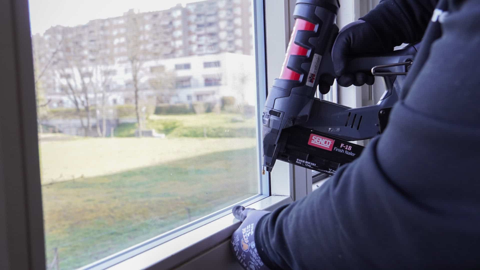 Vitrier utilisant un cloueur pneumatique sur un cadre de fenêtre