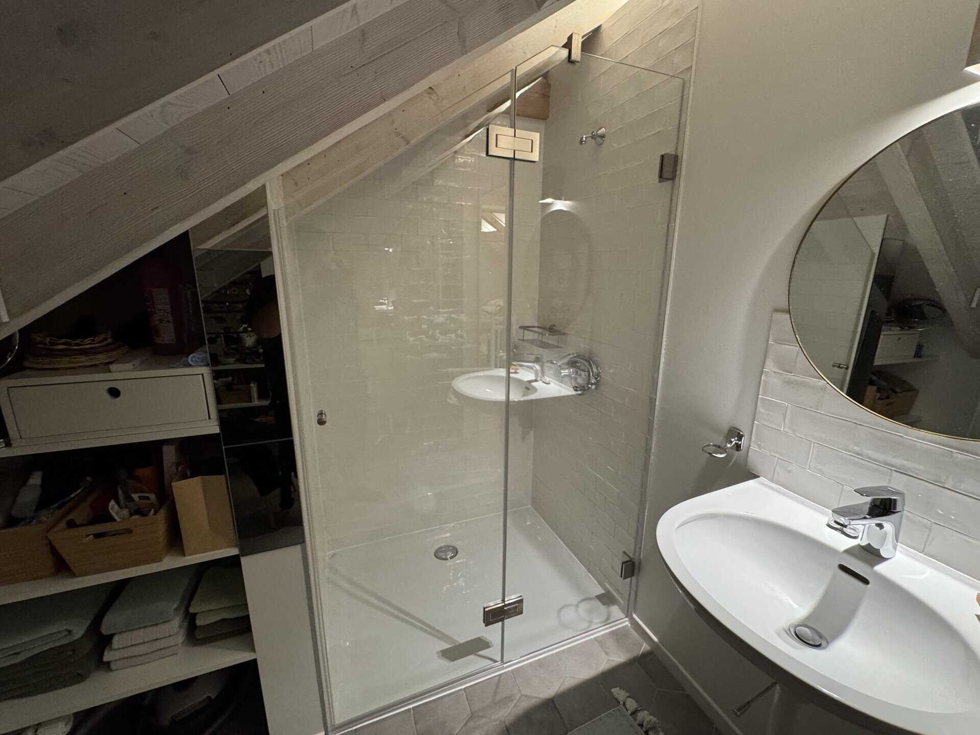 Salle de bain sous combles avec paroi de douche en verre