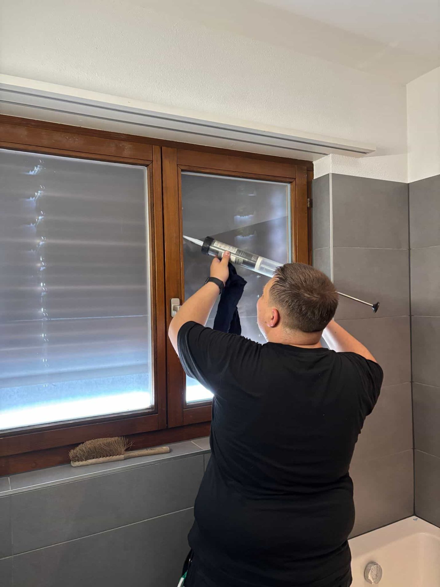 Vitrier appliquant du silicone sur une fenêtre de salle de bain